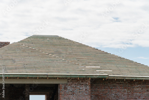 Construction of a red brick house. The house is not covered with metal tiles. Roof construction