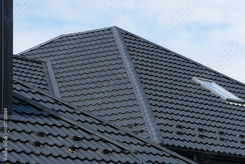 A house with a skylight plastic window and a black corrugated iron roof. Modern roof made of metal