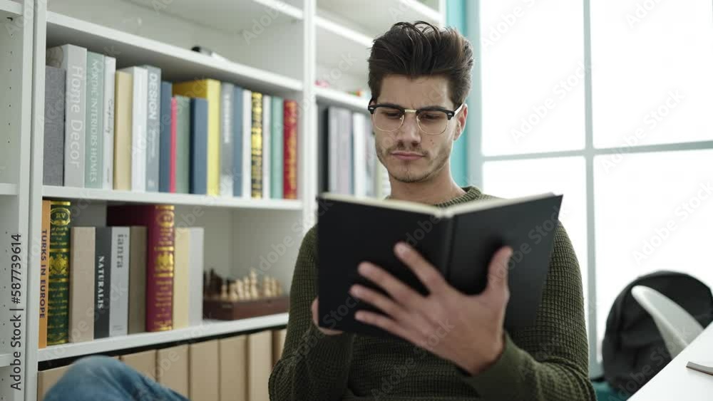 Young hispanic man student reading book studying at library university Young hispanic man student reading book studying at library university