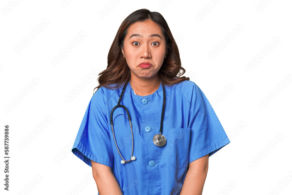 A young nurse chinese woman shrugs shoulders and open eyes confused. A young nurse chinese woman shrugs shoulders and open eyes confused.