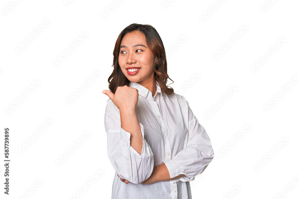 A young chinese woman points with thumb finger away, laughing and carefree. A young chinese woman points with thumb finger away, laughing and carefree.