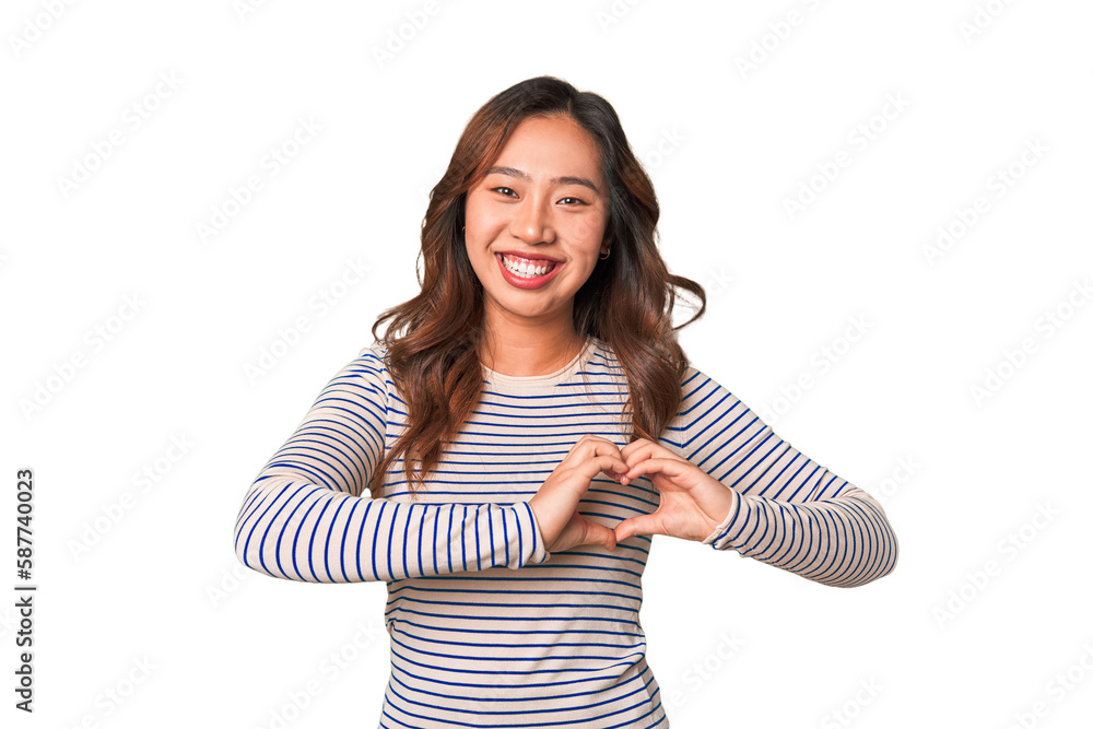 A young chinese woman smiling and showing a heart shape with hands. A young chinese woman smiling and showing a heart shape with hands.