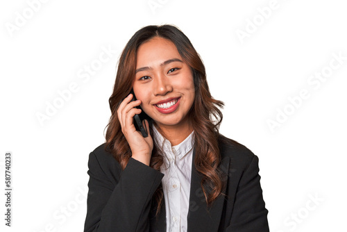 A young chinese businesswoman looks delighted while talking on the phone, likely receiving positive news or accomplishing a successful business deal.
