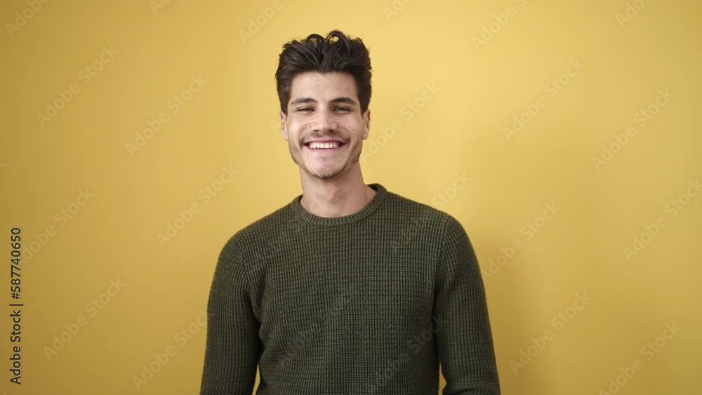 Young hispanic man smiling confident standing over isolated yellow background Young hispanic man smiling confident standing over isolated yellow background
