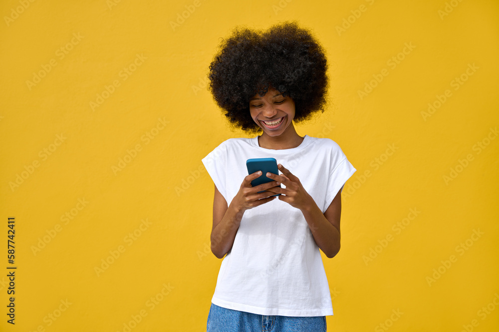 A hipster girl with afro haircut enjoy online communication and online services, wear trendy T-shirt, scroll social media apps on cell phone device isolated on yellow wall. Technology and applications A hipster girl with afro haircut enjoy online communication and online services, wear trendy T-shirt, scroll social media apps on cell phone device isolated on yellow wall. Technology and applications