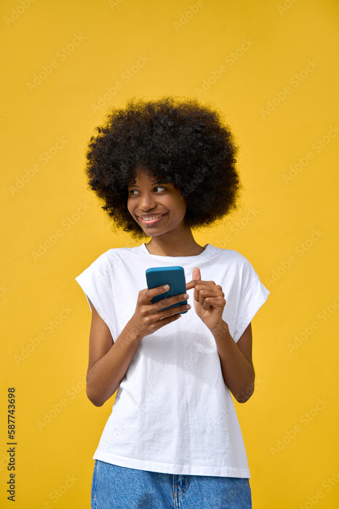 A vertical portrait of hipster girl with afro haircut enjoy online communication and online services, scroll social media apps on cell phone device isolated on yellow wall. Technology and applications A vertical portrait of hipster girl with afro haircut enjoy online communication and online services, scroll social media apps on cell phone device isolated on yellow wall. Technology and applications