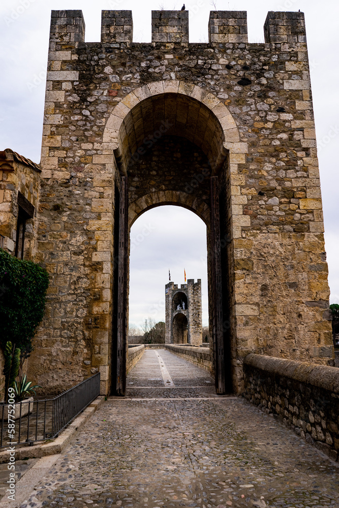 A stone door in a medieval village in Spain under grey sky