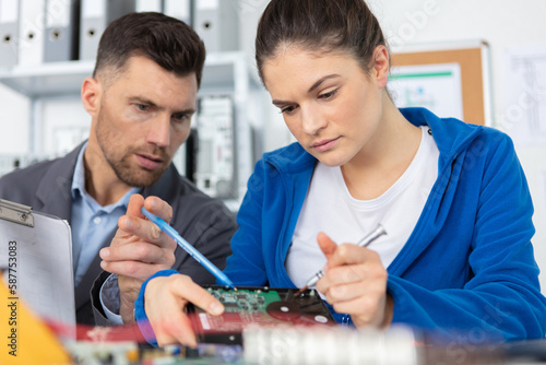 young woman apprentice fixes pc component