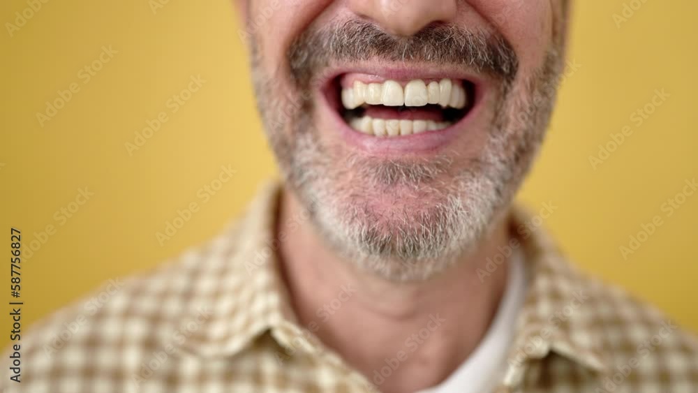 Middle age man smiling confident over isolated yellow background Middle age man smiling confident over isolated yellow background
