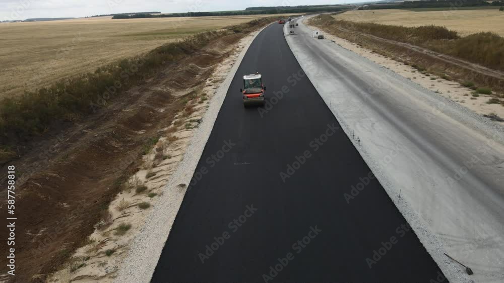 Roller presses asphalt covering on road lane at construction site aerial view. Contemporary highway maintenance during roadworks Roller presses asphalt covering on road lane at construction site aerial view. Contemporary highway maintenance during roadworks