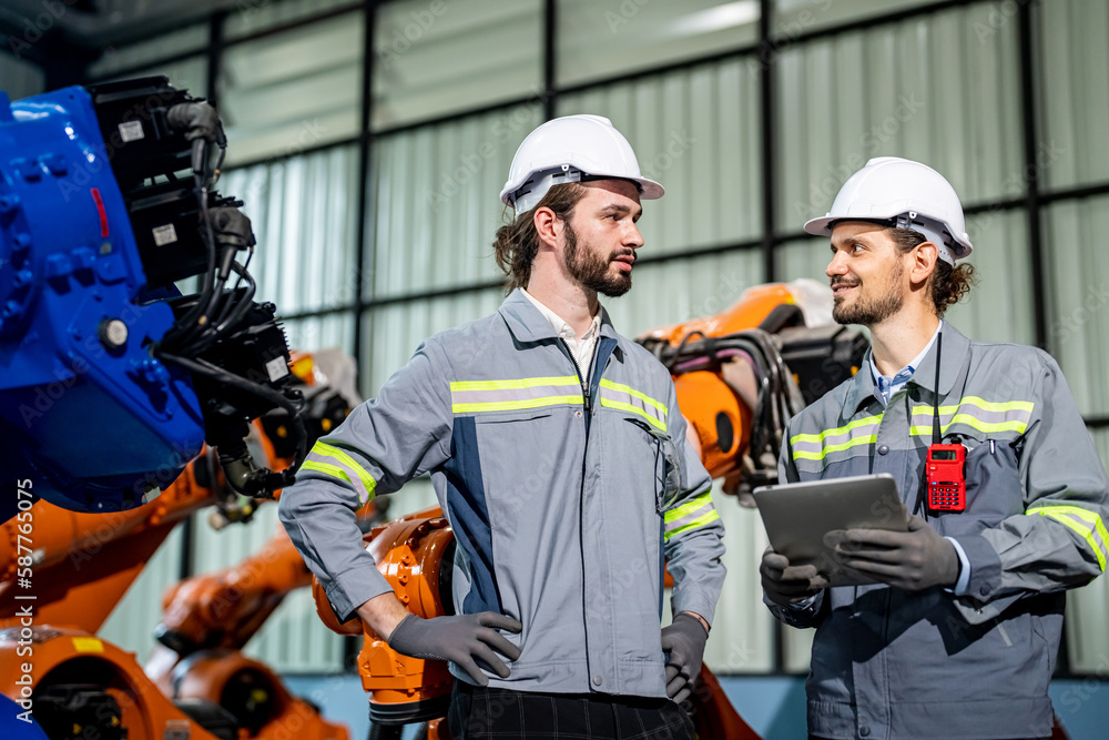 Engineer explaining to controlling robotic welding process to welder in factory. Engineer explaining to controlling robotic welding process to welder in factory.