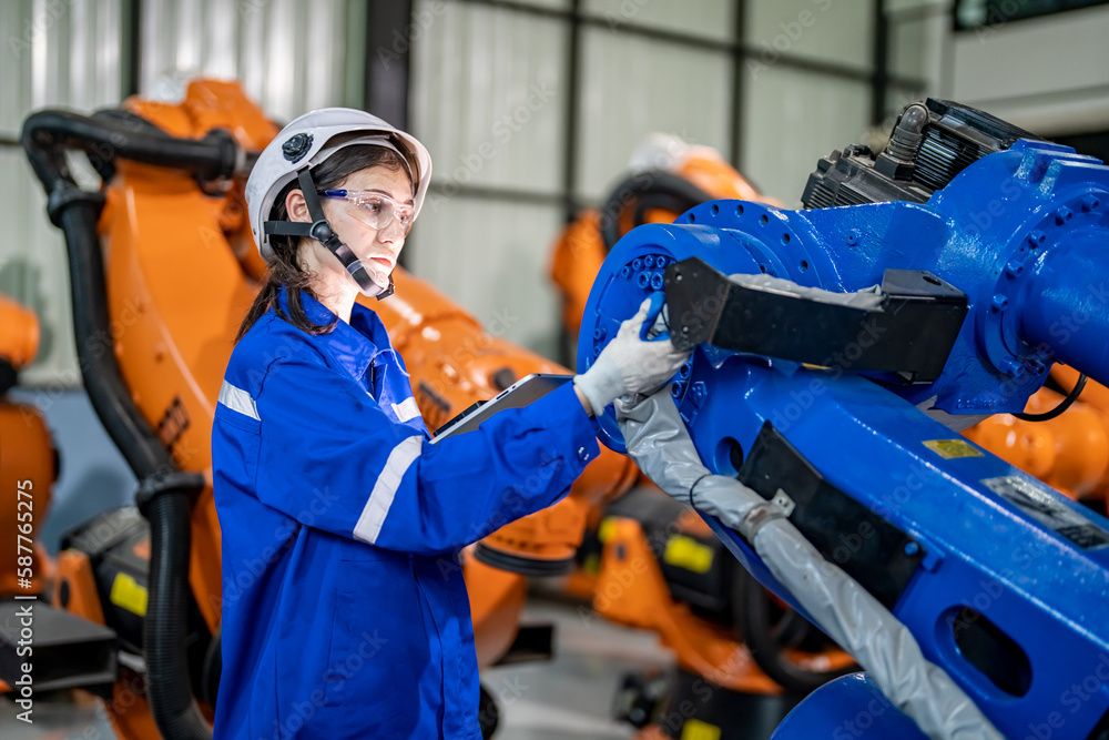 Fototapeta premium Engineer inspecting automatic robot arms and machines in factory.