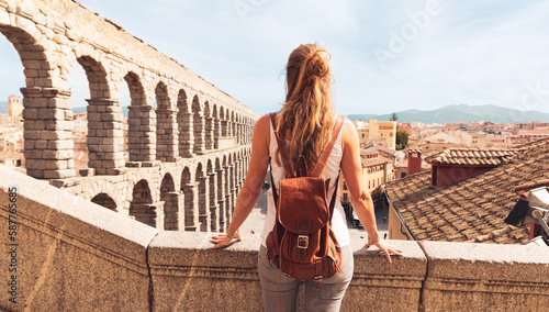 Tourism at Segovia, rear view of woman tourist enjoying view of Roman aqueduct on plaza del Azoguejo in Spain