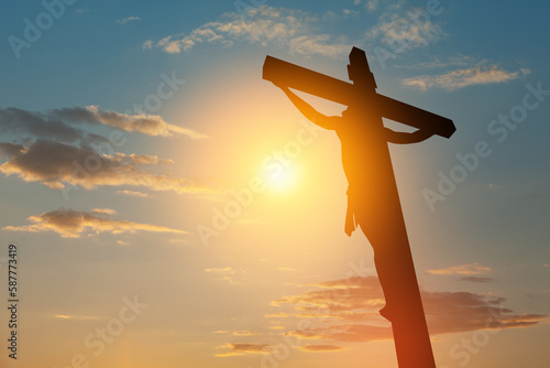 Silhouette of the crucified Jesus Christ on the cross on background of sunset sky. photo