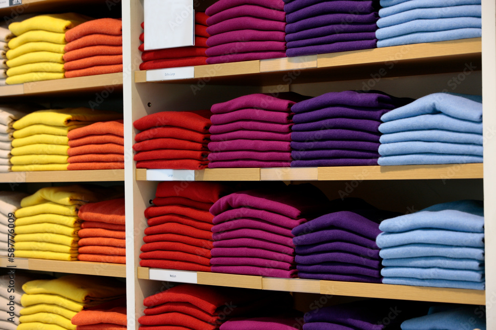 Stacks of colorful cashmere sweaters on shelves in retail store.