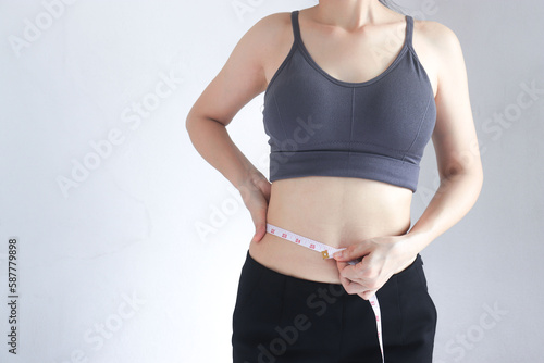  A woman measures her waist with a tape measure
