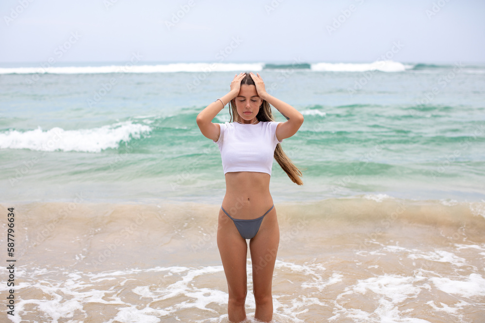 Beautiful young woman in a white cropped t-shirt comes out of the ocean. Beautiful young woman in a white cropped t-shirt comes out of the ocean.