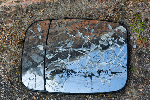 A broken car mirror lies on the floor of an industrial estate