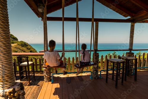 Corfu, Grece - July 10, 2020 - Kids having fun on the swing with amazing view on the sea