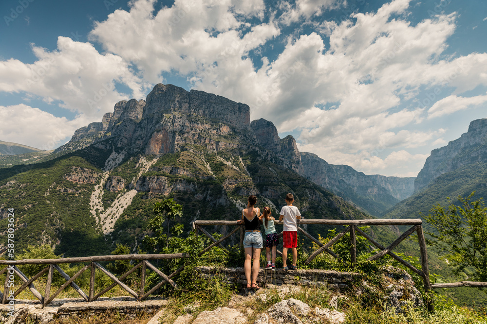 Naklejka premium Family (mother, son, daughter) watching panorama of beautiful Vikos George in Pindus Mountain (Vikos National Park), Greece