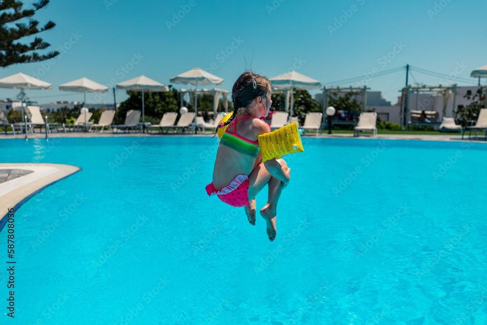 Naxos, Grece - July 20, 2020 - Girl jumping to the pool in the small family hotel on Naxos Island