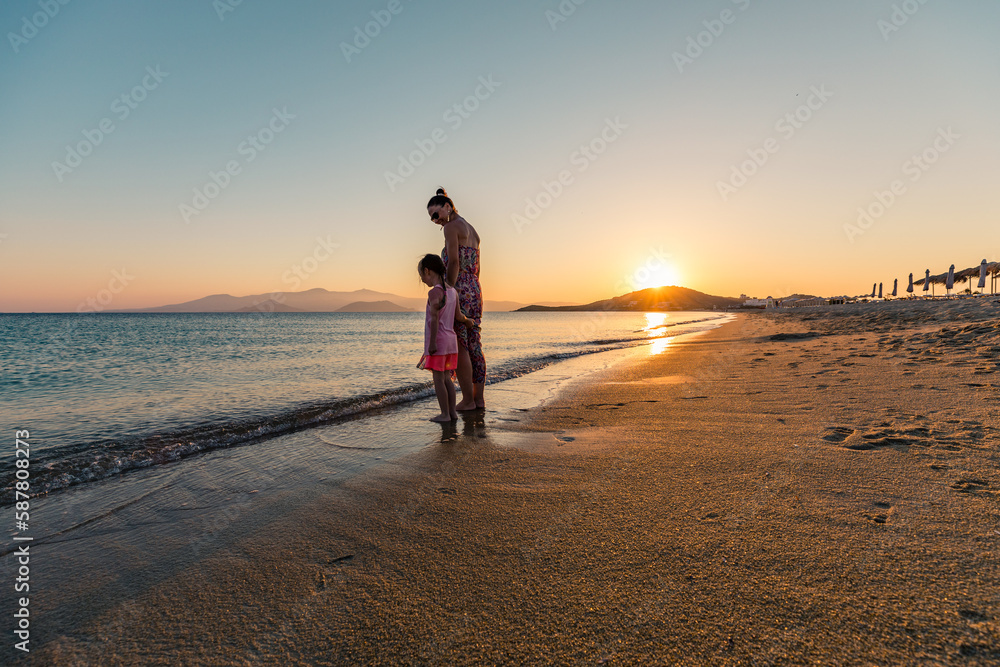 Naxos, Grece - July 20, 2020 - Mother and children watching amazing sunset over Naxos Island