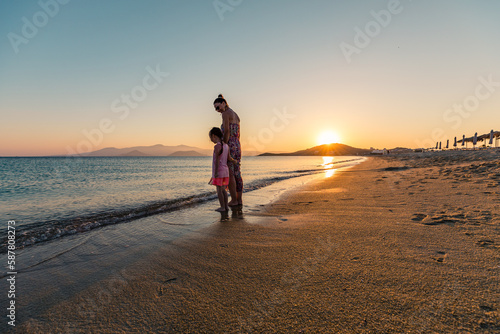 Naxos, Grece - July 20, 2020 - Mother and children watching amazing sunset over Naxos Island