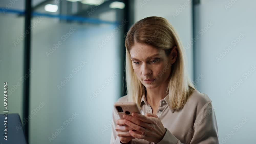 Serious lady reading cellphone message cabinet close up. Woman checking laptop Serious lady reading cellphone message cabinet close up. Woman checking laptop