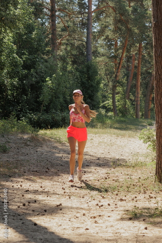 sporty woman runs in forest among trees. fitness, yoga for health of body and mental state. taking care of body, muscles and spine. happy lady in sportswear with long hair on jog © MyJuly