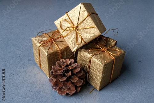 objet de décoration avec 3 paquets cadeau doré et un pomme de pin sur un fond gris en béton ciré image d'illustration pour cadeau de noël et art de la table 