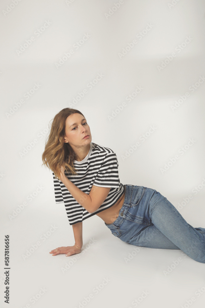 Fashion portrait of young woman in relaxed wide jeans and striped t shirt on the white background Fashion portrait of young woman in relaxed wide jeans and striped t shirt on the white background