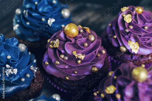 Set of chocolate cupcakes with dark blue and purple cream and golden sprinkles