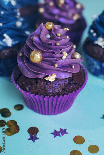 Set of chocolate cupcakes with dark blue and purple cream and golden sprinkles