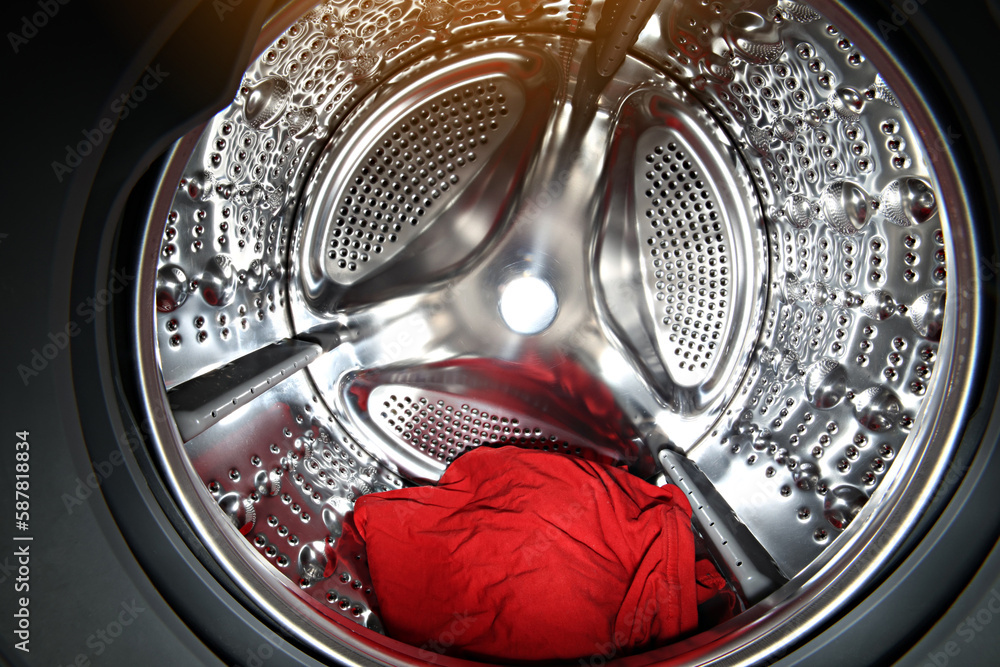 View of the tumble dryer or washing machine drum with red clothes inside.  Laundry day. Daily household chores. Domestic and Household Appliance. Home  Innovation. Stock Photo | Adobe Stock