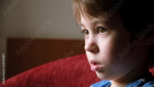 6 year boy looking at screen. Child is watching TV, cartoons or video. Home online education concept. The concentrating kid. 4K. Tired unblinking eyes. Mouth breathing. Parental content control. photo