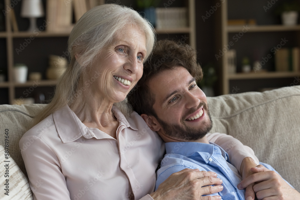 Cheerful senior old grandma hugging handsome adult grandkid man on home ...