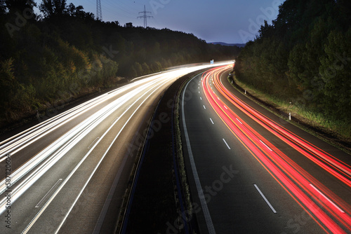 white and red traces of light from moving cars on highway at night six lines autobahn car road long exposure shot fast moving cars