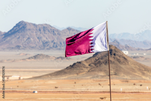 Qatar flag waving on the wind in Saudi Arabian desertwith mountains in background, Al Ula, Saudi Arabia photo