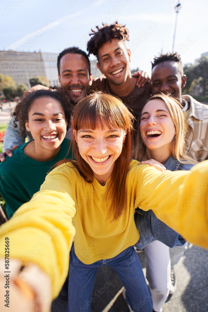Vertical photo of a Group of happy friends posing for a selfie on a spring day as they party together outdoors. Group of multicultural friends having a good time together on the weekend. - obrazy, fototapety, plakaty 