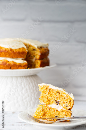 Carrots cake with cream cheese in front of a white brick wall
