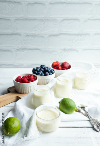 Lime posset with berries in front of a white brick wall