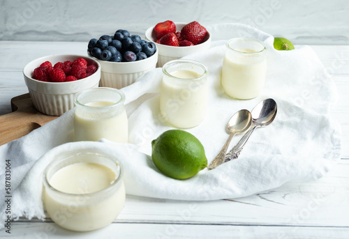 Lime posset with berries in front of a white brick wall