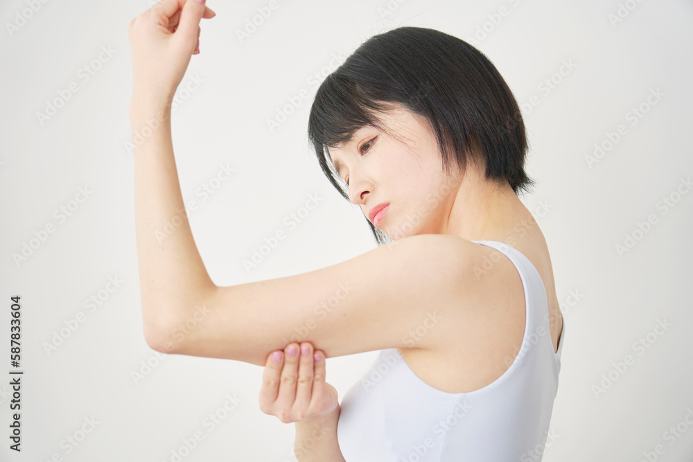 二の腕を触る女性 二の腕を触る女性