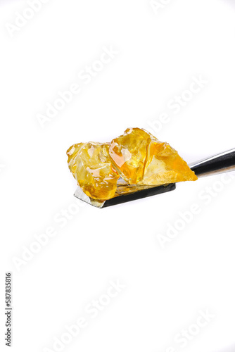 Close-up of some Cannabis diamonds sitting on a titanium tool with a seamless white background. 