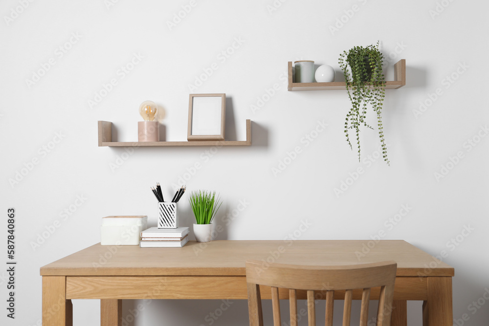 Fototapeta premium Comfortable workplace with wooden desk near white wall at home