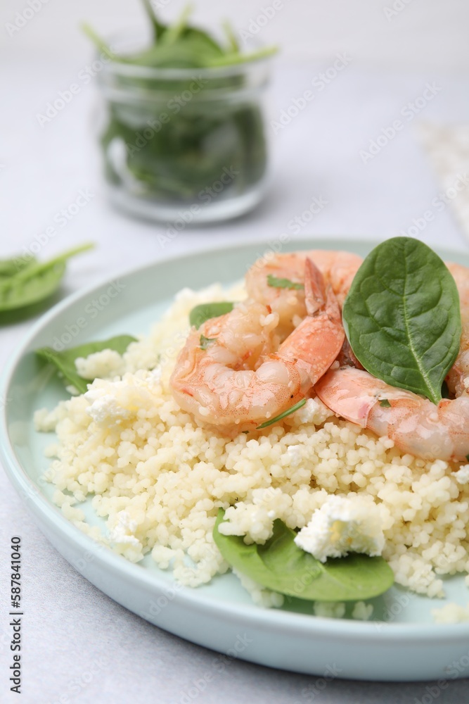 Plate of delicious couscous with shrimps and spinach on white table, closeup Plate of delicious couscous with shrimps and spinach on white table, closeup