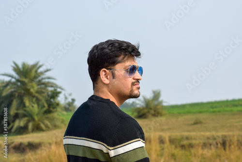 Male model posing for photographs. He wearing sun glasses and woolen wear with strips