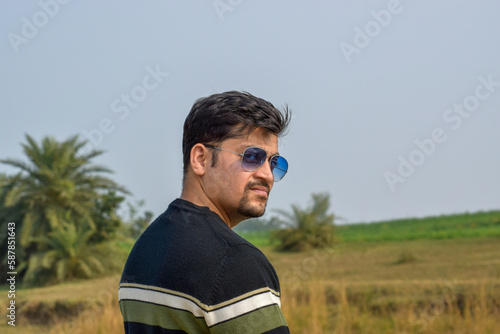 Male model posing for photographs. He wearing sun glasses and woolen wear with strips