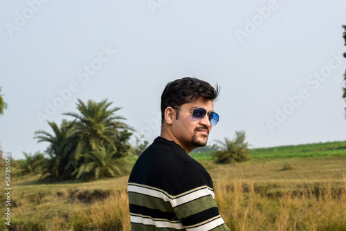 Male model posing for photographs. He wearing sun glasses and woolen wear with strips photo