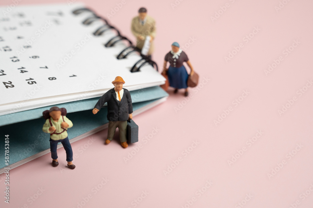 Miniature model people, travelers standing with the calendar on pink background, traveling and planning concept Miniature model people, travelers standing with the calendar on pink background, traveling and planning concept